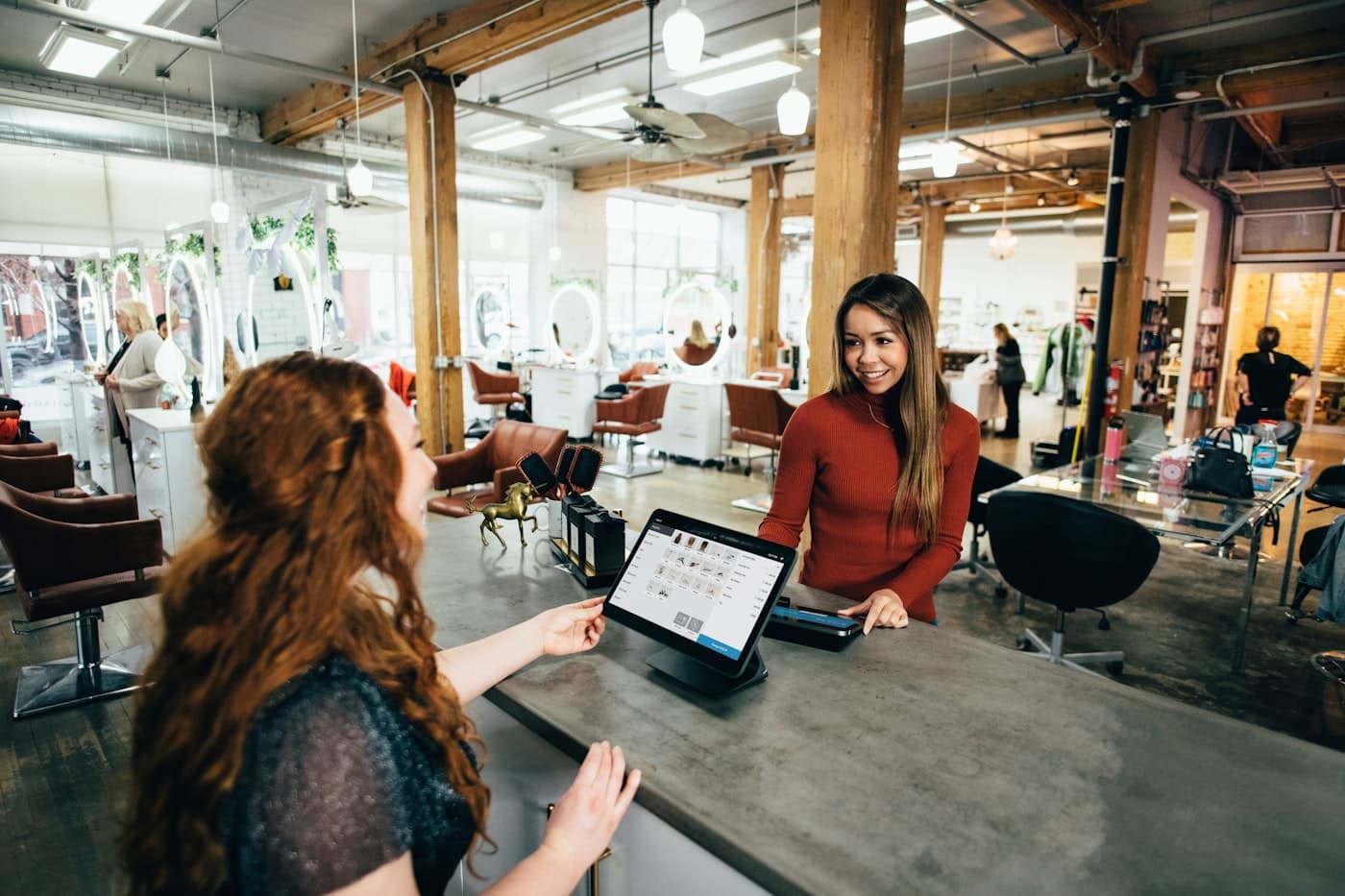 A salon receptionist checking in a customer on a tablet
