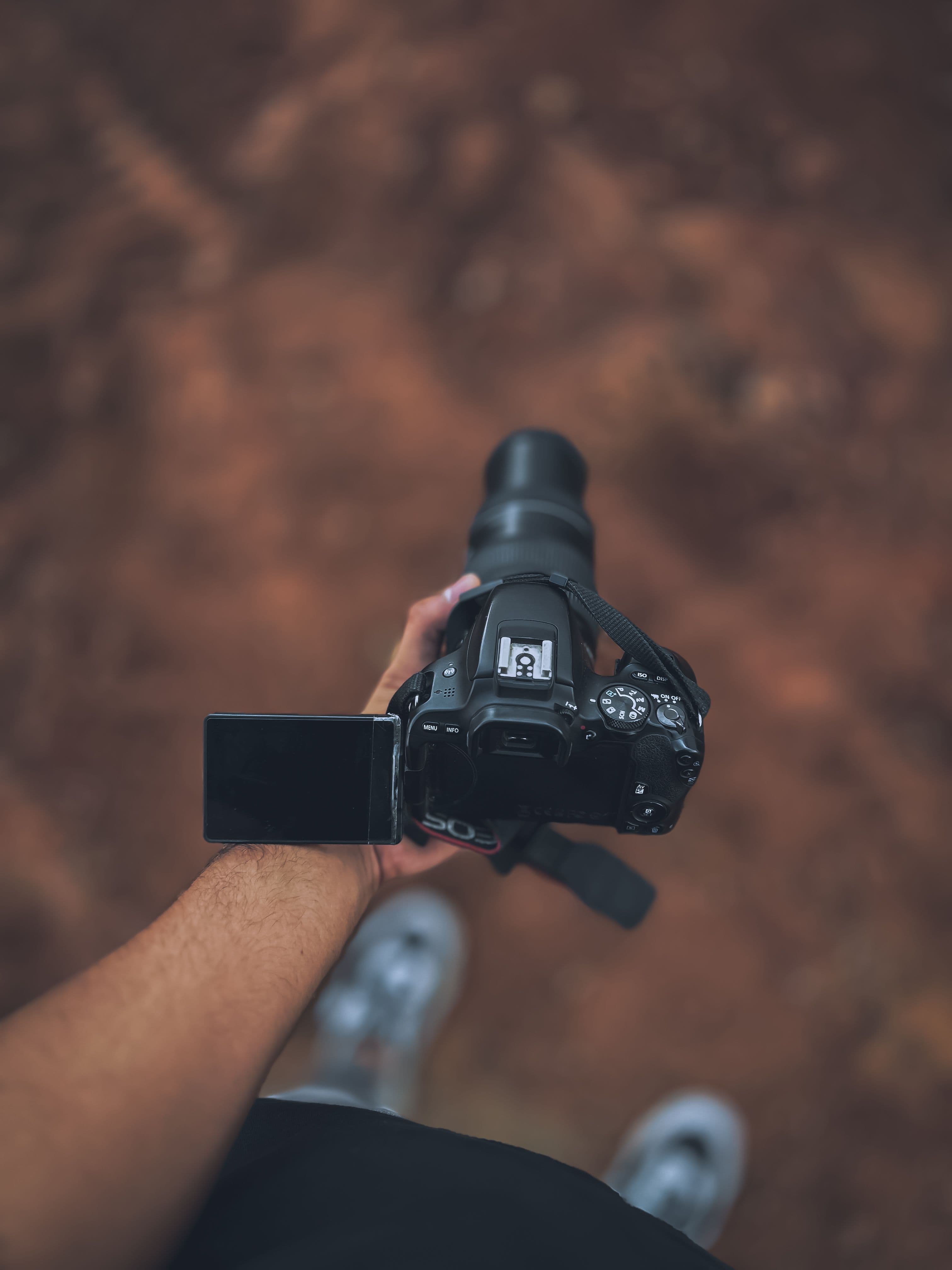 A videographer holding a camera with a flip-out screen